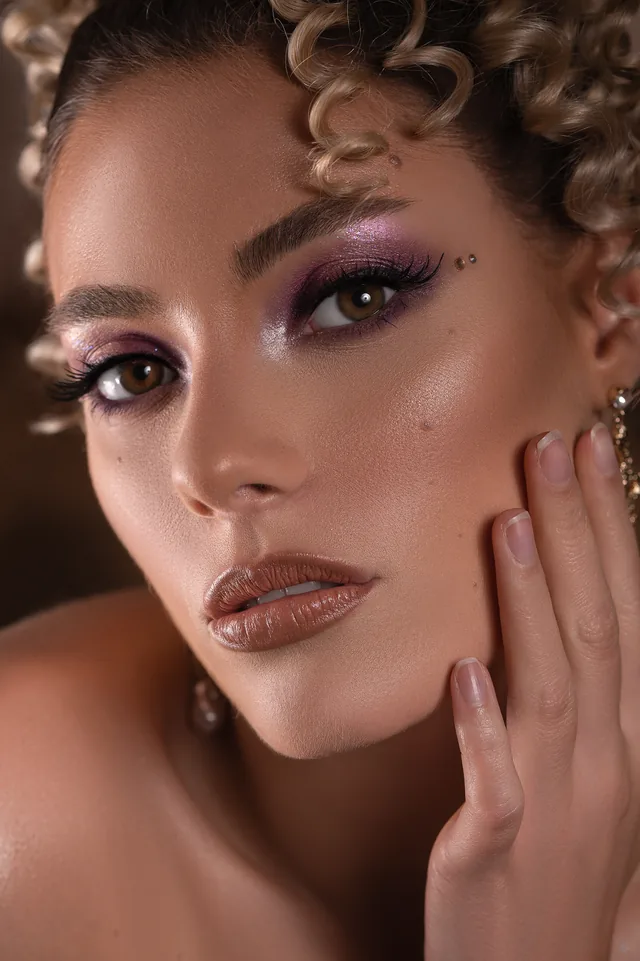 Lila Smokey Eyes mit Nude-Lippen und Lockenfrisur