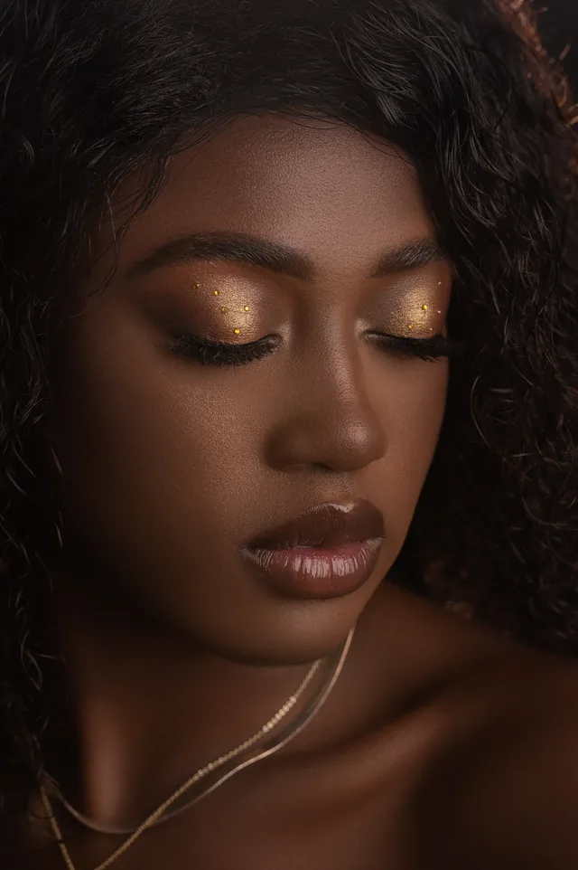 Goldener Glitzer-Lidschatten auf dunkler Haut mit Nude-Lippen
